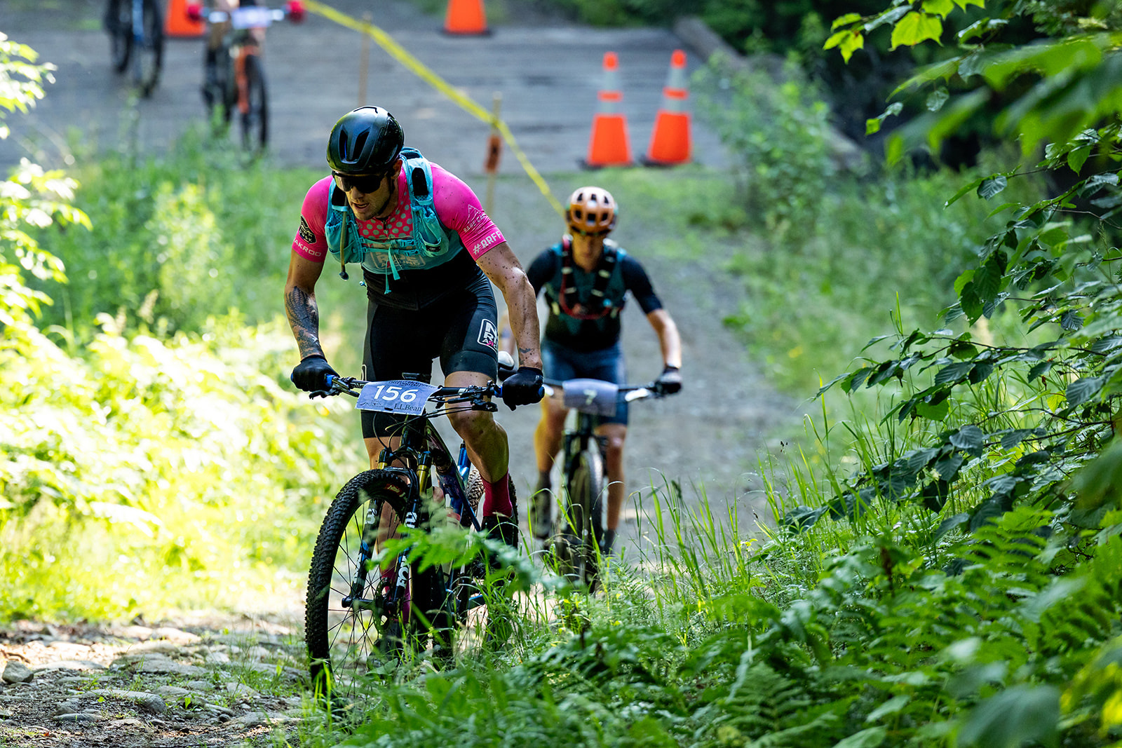Racer descending a rocky trail through thick ferns