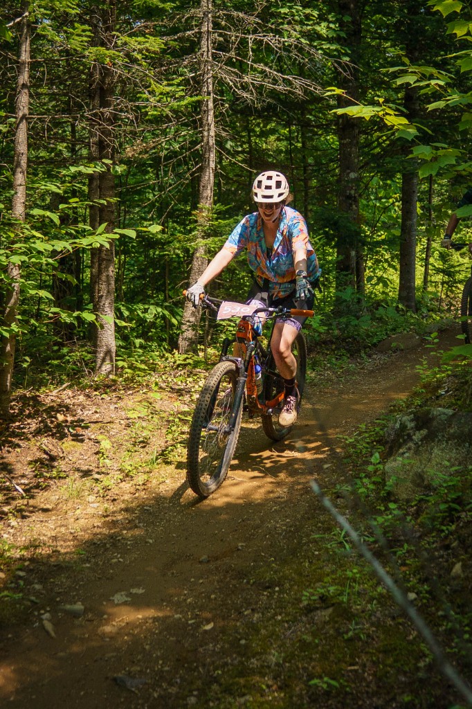 Grinning racer in a colorful jersey on shaded singletrack